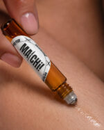 dedo polegar e indicador aplicando perfume com frasco cilíndrico feito de vidro com ponta aplicadora redonda de aço deslizante no braço