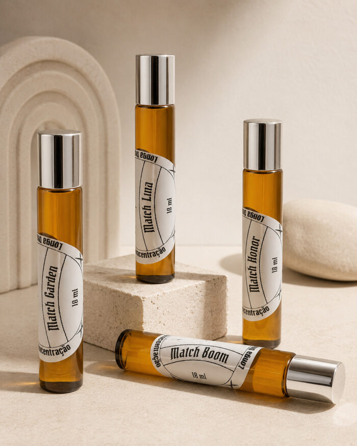 Três frascos cilíndricos de perfume portátil feitos com vidro âmbar e tampas prateadas na vertical dispostos em forma de pódio e um frasco na horizontal sob pedras de granito bege