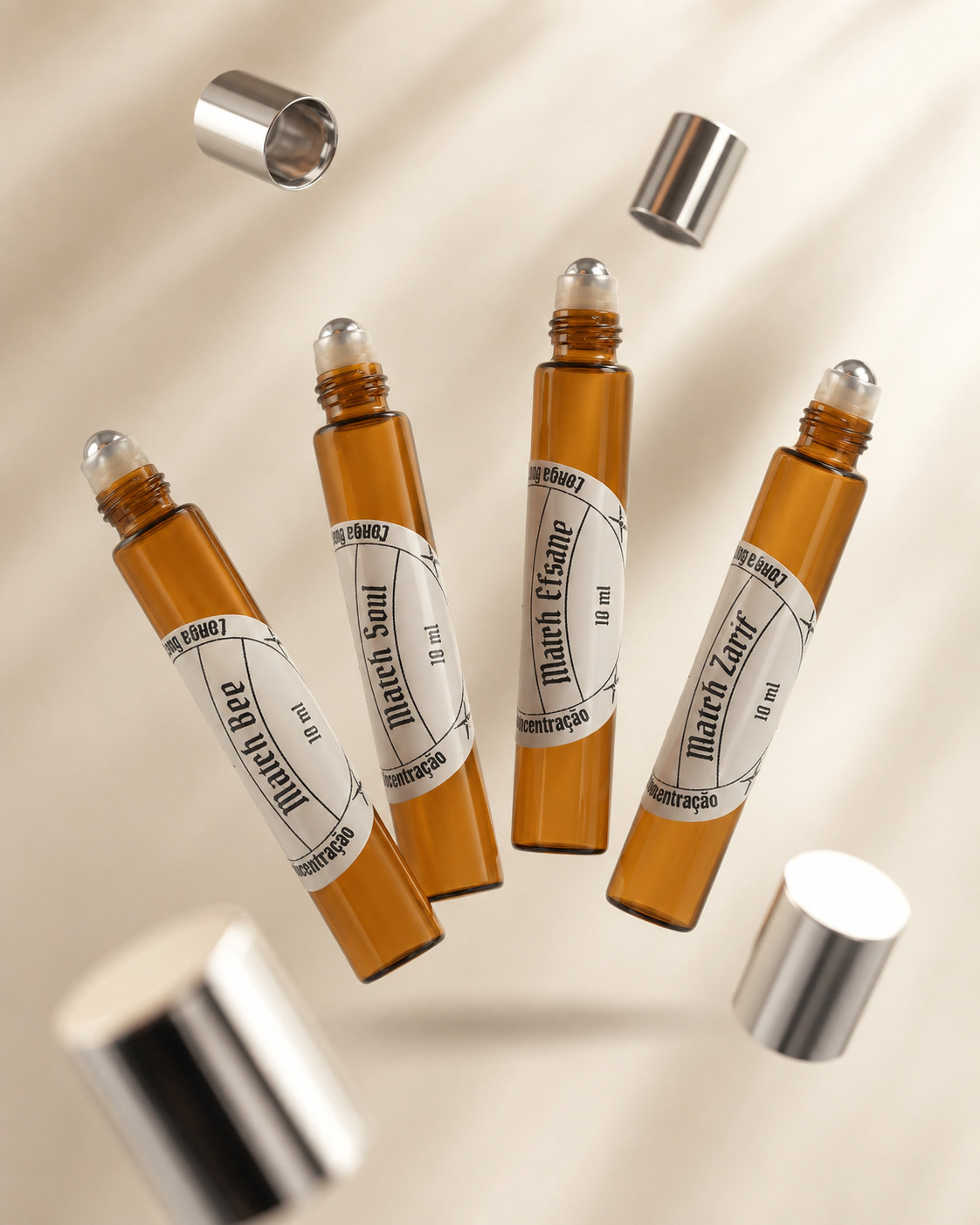 kit-match-duale-perfumes-roll-on-eau-de-parfum-composicao-explodida-matchii quatro frascos de vidro cor âmbar de Perfumes roll on com aplicadores de esfera metálica a mostra e tampas suspensas efeito gravitacional