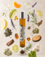 frasco de perfume portátil cilíndrico de vidro âmbar com tampa cromada com rótulo redondo branco match soul na vertical rodeado por fatia de limão pedaço de madeira de cedro alecrim lavanda gomo de tangerina âmbar